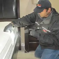 Bed bug inspection technician checking a mattress and bed frame for signs of infestation in Allentown, PA