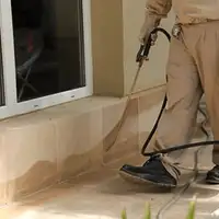 General pest control technician spraying exterior perimeter around a home in Allentown, PA